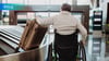 man alone in wheelchair with luggage at turnstyle in airport