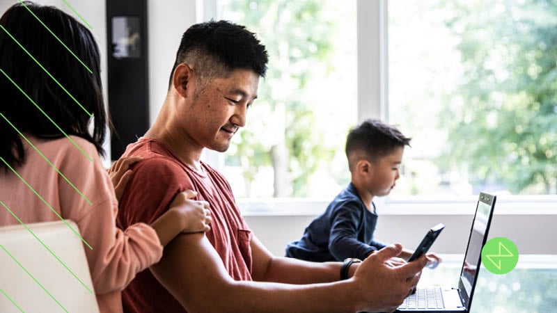 Man on laptop and mobile phone, being targeted across devices, in an omnichannel marketing campaign